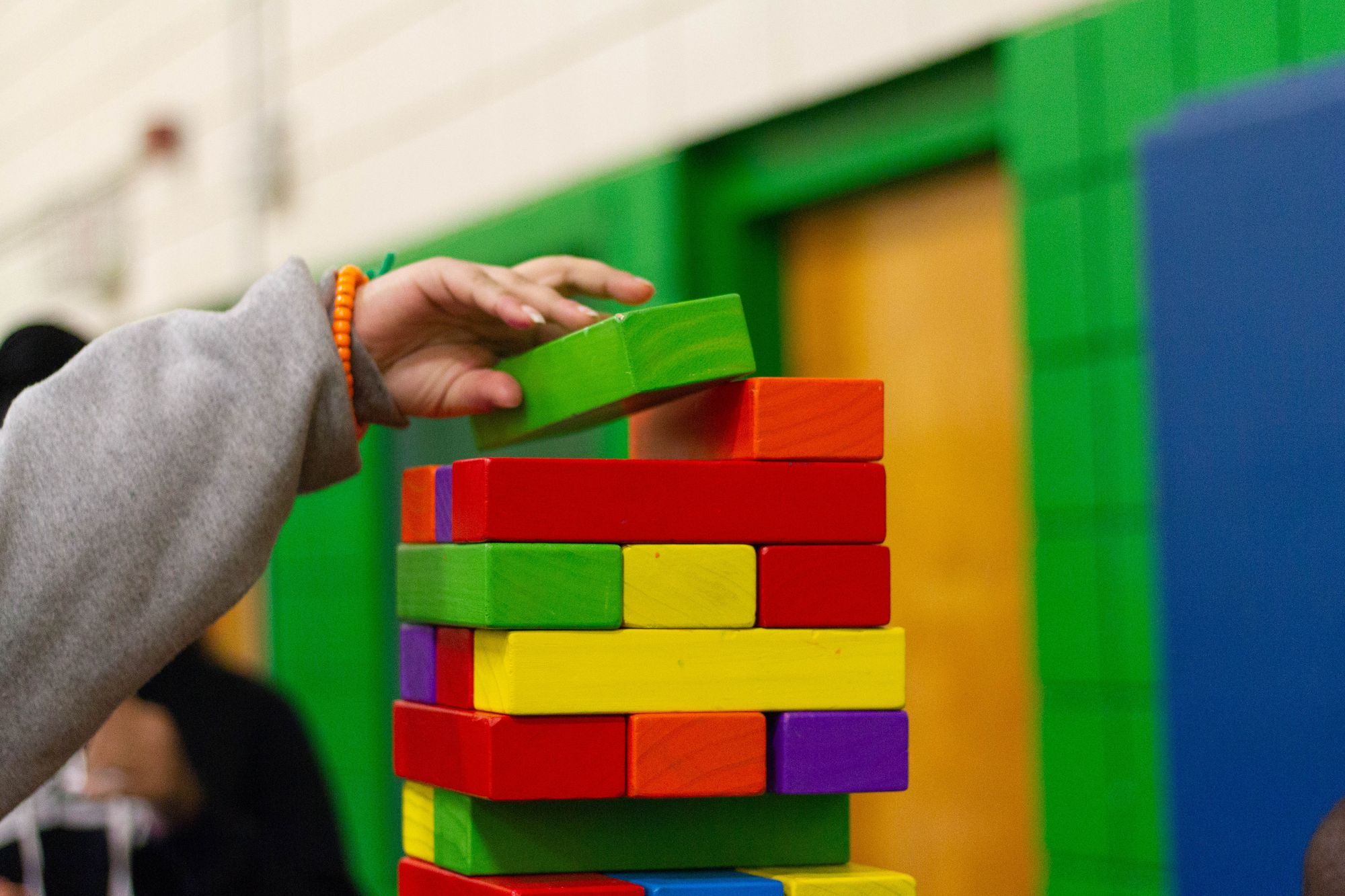 a child putting a piece on colorful toys to build a tower from toys