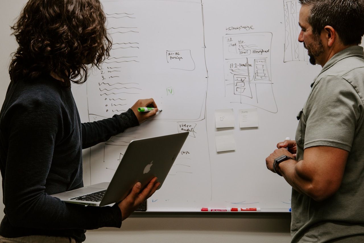 two people making a strategy on whiteboard by drawing and discussing