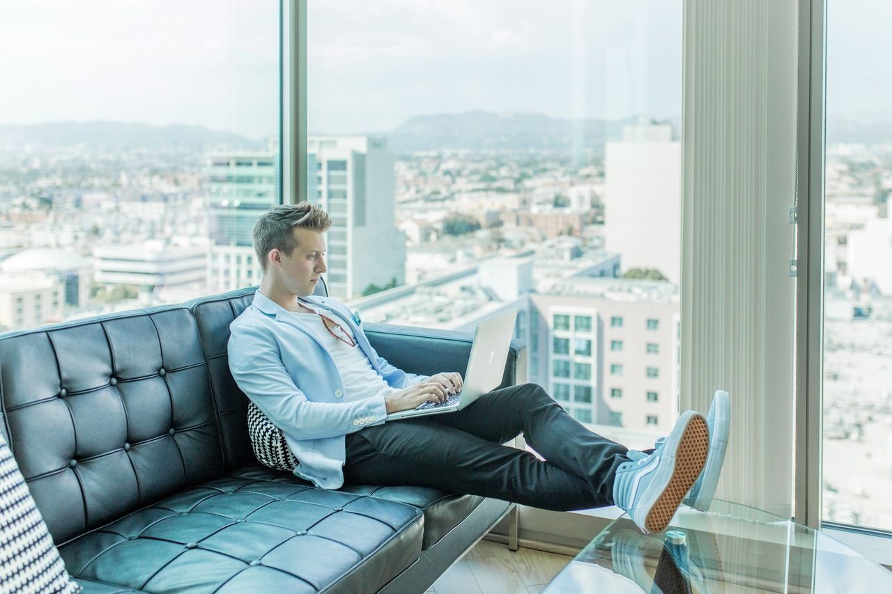 a man sitting on a couch and researching on his laptop in his office