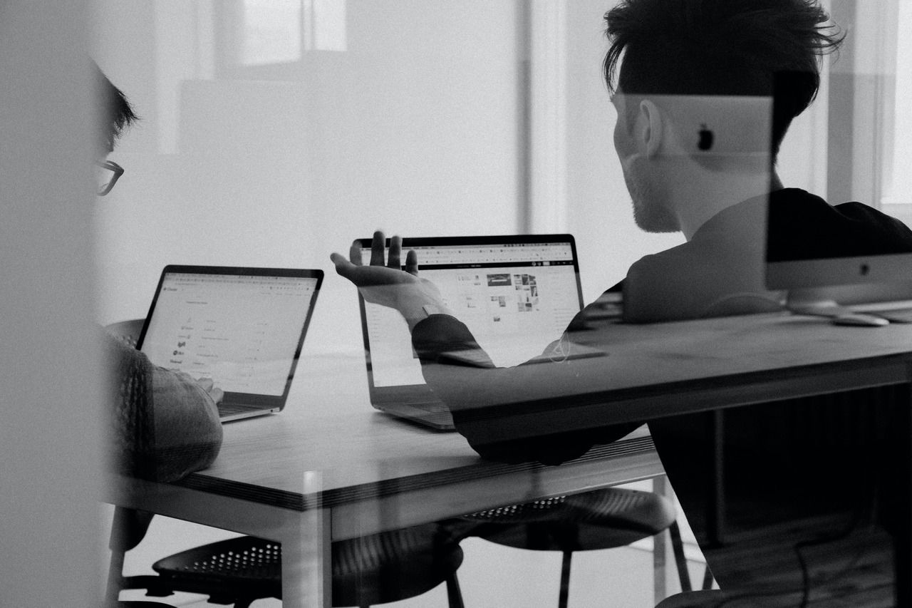 two colleagues discussing an issue by looking at their laptops in a meeting room