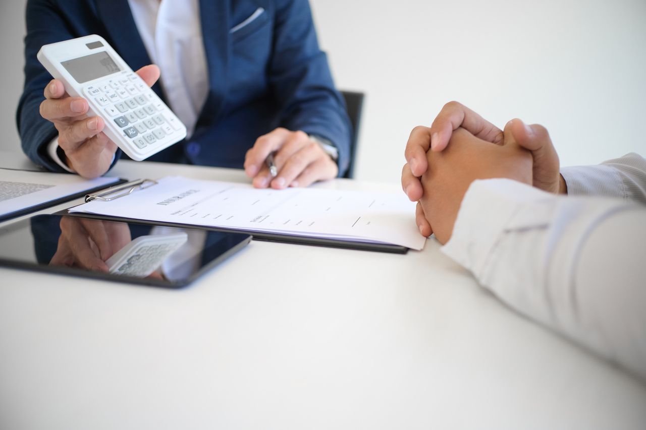 a businessman showing calculator to a person who is probably a client